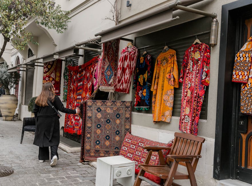 External view of an apartment building showing a clothesline strung across the balcony, with a patterned red and gold rug and a plain white towel hanging to dry. The building’s facade features textured concrete and rectangular windows, one of which is open with a white curtain visible inside. The scene is illuminated by natural daylight, highlighting the weathered surfaces and the drying laundry, exemplifying typical residential exterior spaces. This image relates to surface cleaning and maintenance as part of routine domestic hygiene, consistent with Kensington Carpet Cleaners' services discussed in the Kensington High Street Rug Cleaning Guide for Local Homes.